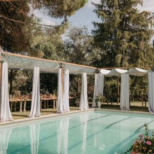 Pergolas de madera para eventos decoracion boda con cortinas elegantes alrededor de piscina para dar sombra