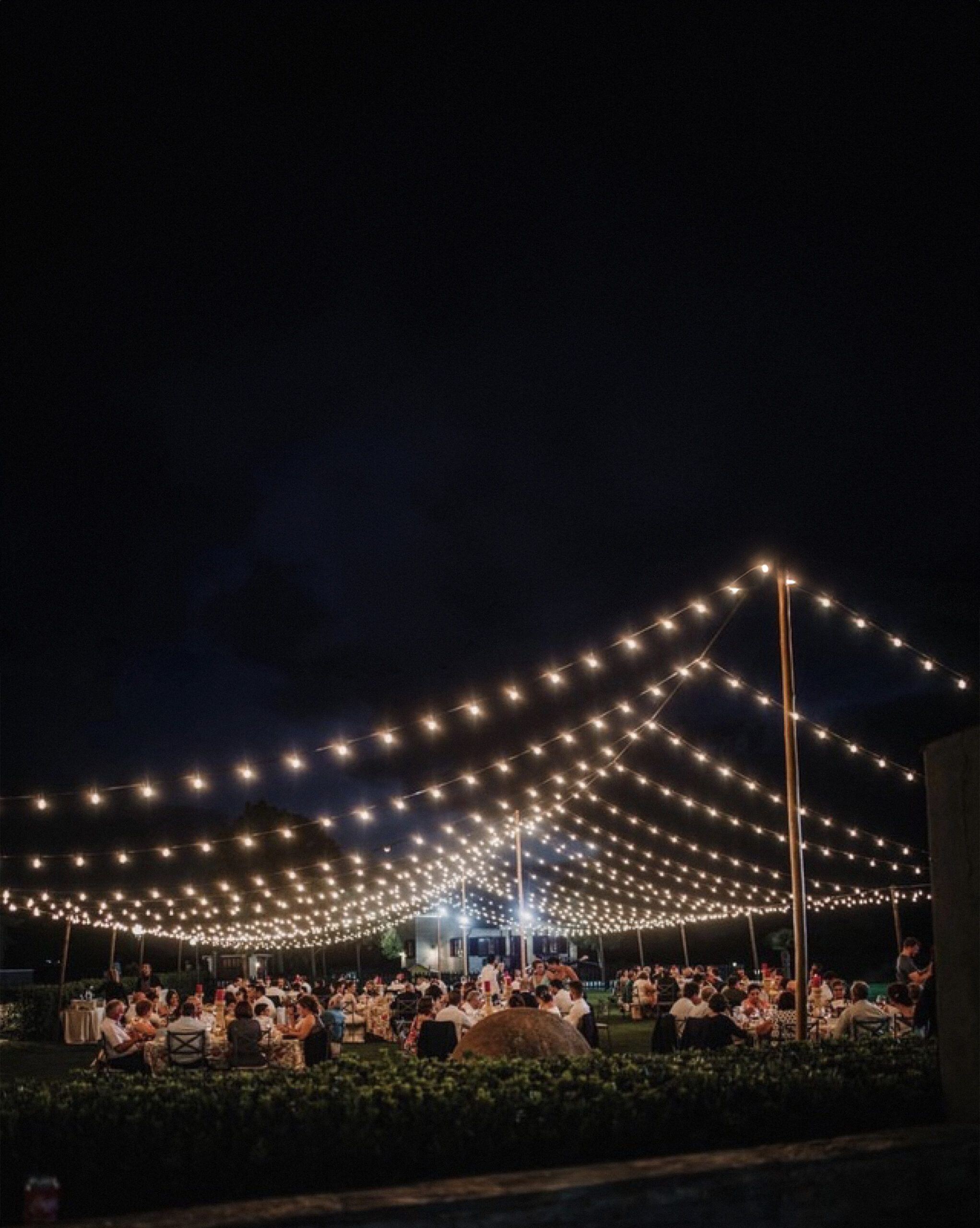 Instalación de guirnaldas de bombillas tipo LED vintage dispuestas en forma de techo a dos aguas para la iluminación de una carpa o espacio abierto.