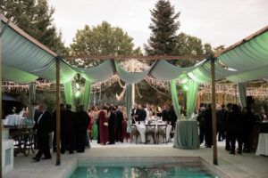 Pergolas de madera para sombra en evento alrededor de piscina con iluminacion