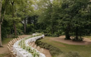 Primer plano de mesa serpenteante para boda con mantel blanco drapeado y montaje de copas de cristal.