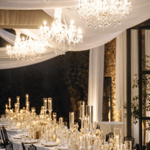 Montaje de mesa serpenteante con mantelería técnica drapeada y lámparas chandelier en el patio de Finca El Campillo.