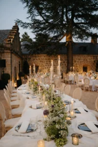 Montaje de mesa serpenteante con mantelería blanca drapeada en los jardines de Finca La Granjilla para una boda de lujo.