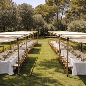 Dos hileras paralelas de pérgolas de madera con lonas blancas cubriendo mesas imperiales largas en un jardín espacioso rodeado de árboles.